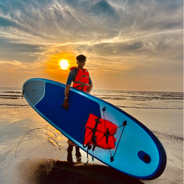 A guy carrying sup on the beach